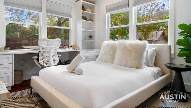 A bedroom with a large bed, a desk with a chair, and a bookshelf.