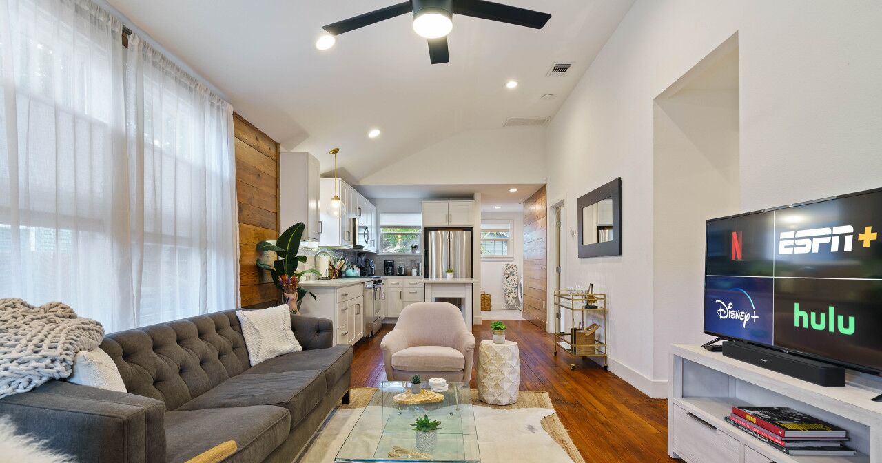 A modern living room with a sofa, coffee table, and TV displaying streaming services.