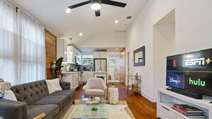 A modern living room with a sofa, coffee table, and TV displaying streaming services.
