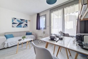 Uma sala de estar moderna com sofá, mesa de jantar e área de cozinha com fogão.