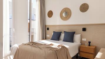 A hotel room with a bed, bedside tables, a nightstand, and a view of the outside.