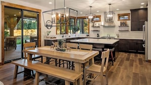 Una cocina moderna con una isla central, suelo de madera e iluminación colgante.