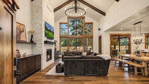 Una sala de estar amplia con chimenea, ventanas grandes y un techo alto con vigas a la vista.