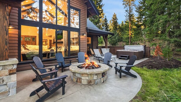 Un patio moderno al aire libre con sillas Adirondack, un hogar a leña de piedra y un jacuzzi.