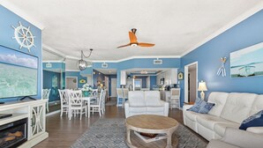 Un salon spacieux avec un canapé blanc, une table basse en bois et un coin repas avec des chaises blanches.