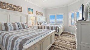 Une chambre avec deux lits, un ventilateur de plafond, une commode et une fenêtre avec des stores.