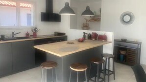 A modern kitchen with a central island, bar stools, pendant lighting, and a built-in oven.