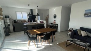 A modern kitchen with a dining area, a sofa, and a coffee table.