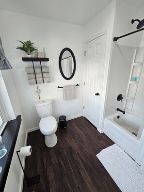 Une salle de bain comprenant des toilettes, un lavabo, un miroir et une baignoire.