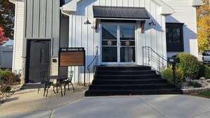 Valkoinen rakennus, jossa on musta ovi, postilaatikko ja kyltti, jossa lukee: ”358 Thomas St.”