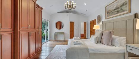 A bedroom with a large bed, a nightstand, a dresser, and a chandelier.