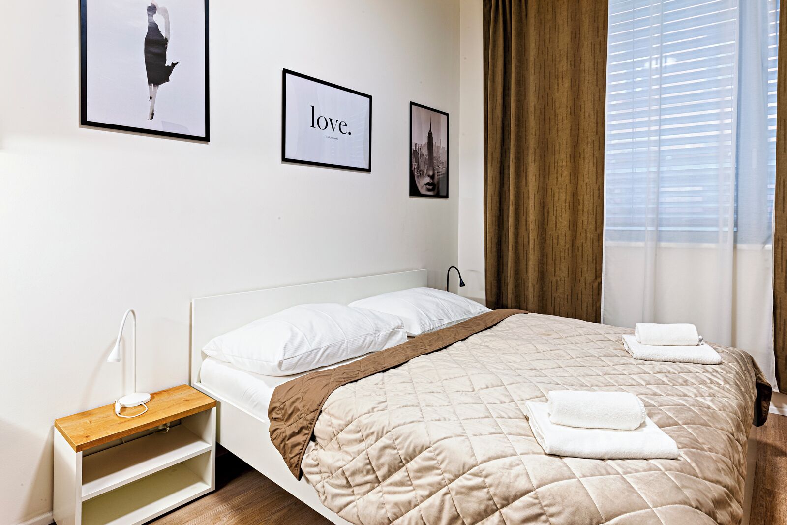 Ein ordentlich eingerichtetes Hotelzimmer mit Bett, Nachttisch und Beistelltisch.