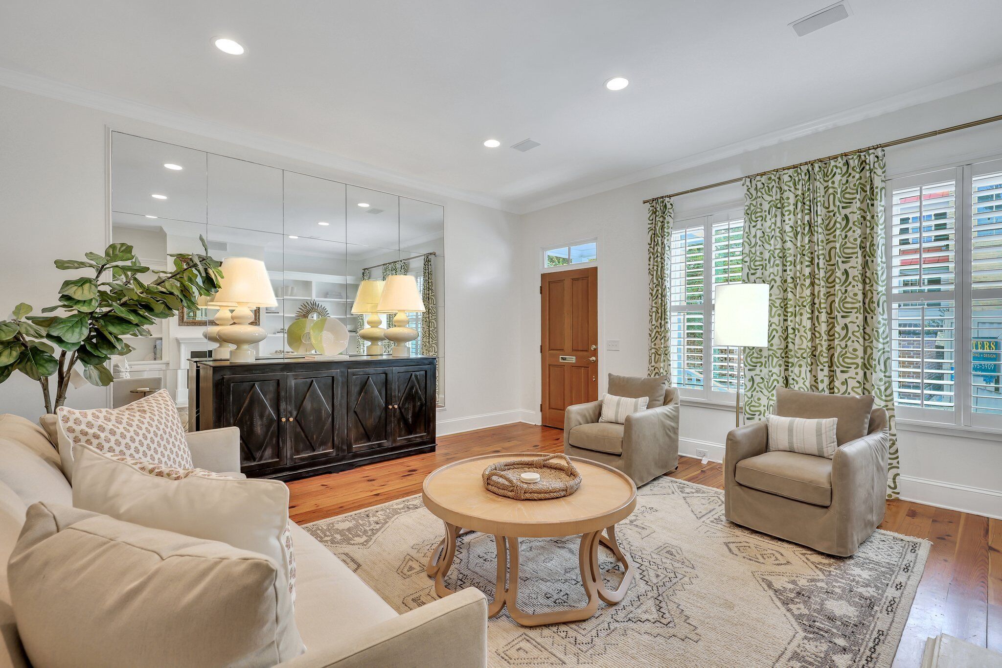 A spacious living room with a large mirror, a round coffee table, and a beige sofa.