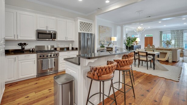 A modern kitchen with white cabinetry, stainless steel appliances, and a bar area with stools. - Luxury Living w/ Private Pool + Parking Steps to River by Lucky Savannah (Savannah)