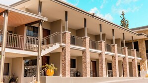A multi-story building with a covered patio area, multiple balconies, and a stone facade.