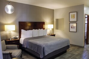 A hotel room with a large bed, two bedside lamps, a wooden headboard, a chair, and a large mirror on the wall. - Hotel El Dorado (Tecate)