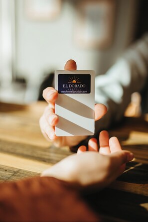 A hand holding a business card with the text "EL DORADO" and a website address. - Hotel El Dorado (Tecate)