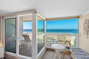A sunlit room with a view of the ocean, a sliding glass door, a white table, and a bench. - Luxury on the Sand – Large Oceanfront Condo La Playa #202D by RVA (Longboat Key)