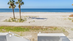 A beach view with palm trees, a clear sky, and a staircase leading to a white building. - Luxury on the Sand – Large Oceanfront Condo La Playa #202D by RVA (Longboat Key)