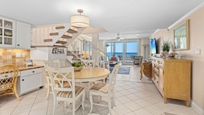 A spacious kitchen with a spiral staircase, a dining area with chairs, and a view to the outside. - Luxury on the Sand – Large Oceanfront Condo La Playa #202D by RVA (Longboat Key)