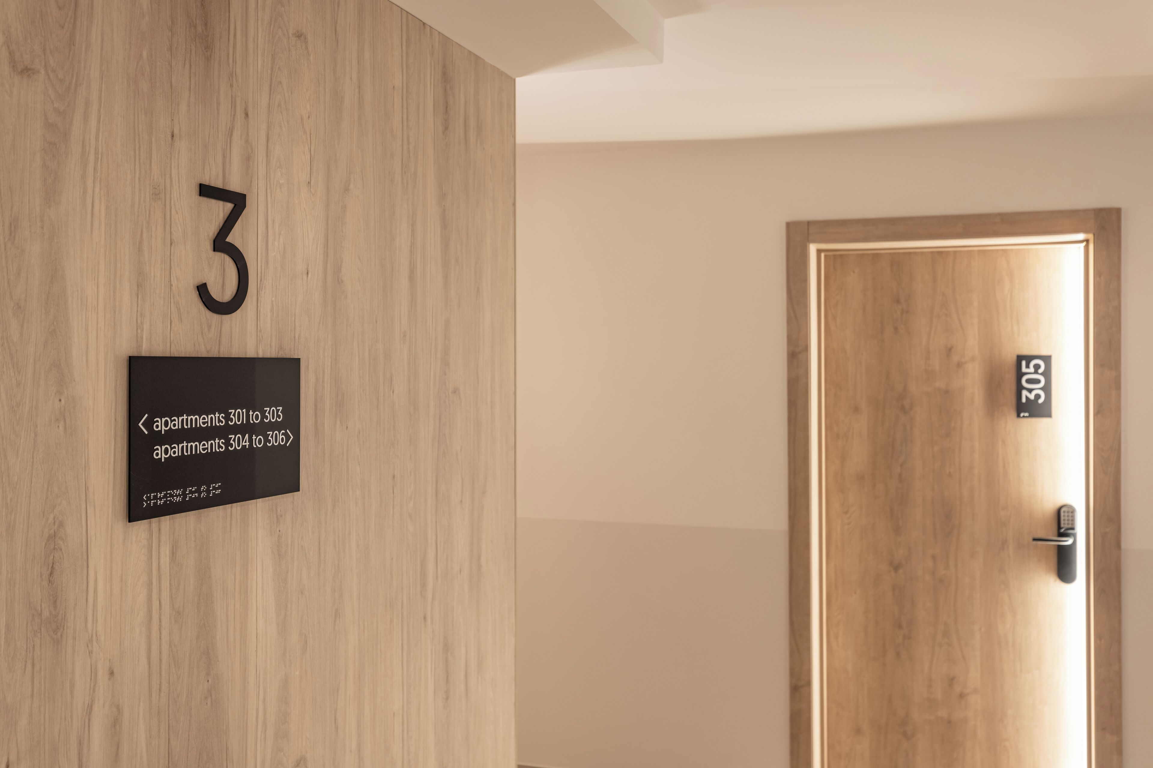 A wooden wall with a number '3' and a sign indicating apartments 301 to 303 and 304 to 306.