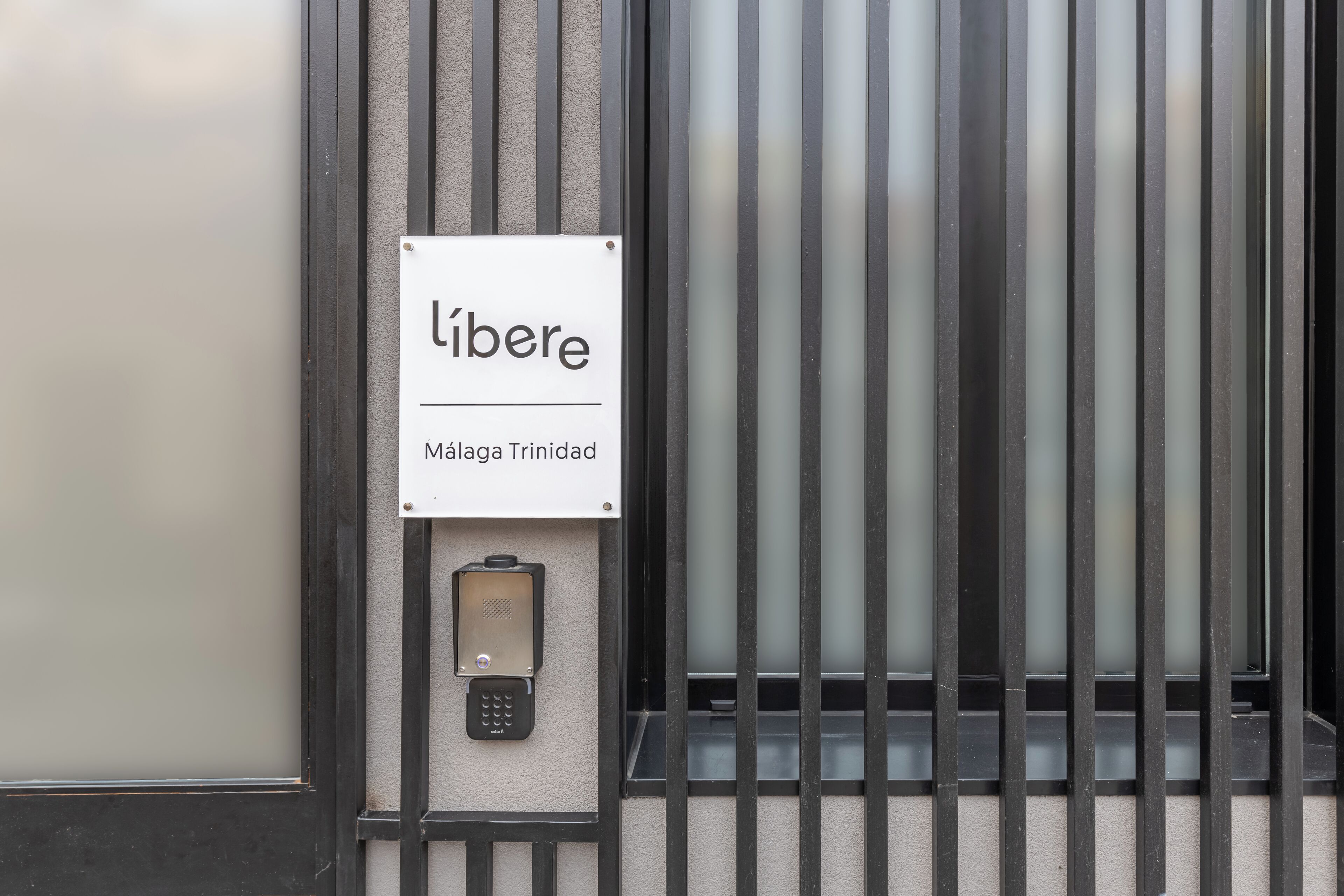 Une porte avec une pancarte indiquant « libere » et « Malaga Trinidad » au-dessus d’un clavier de verrouillage.