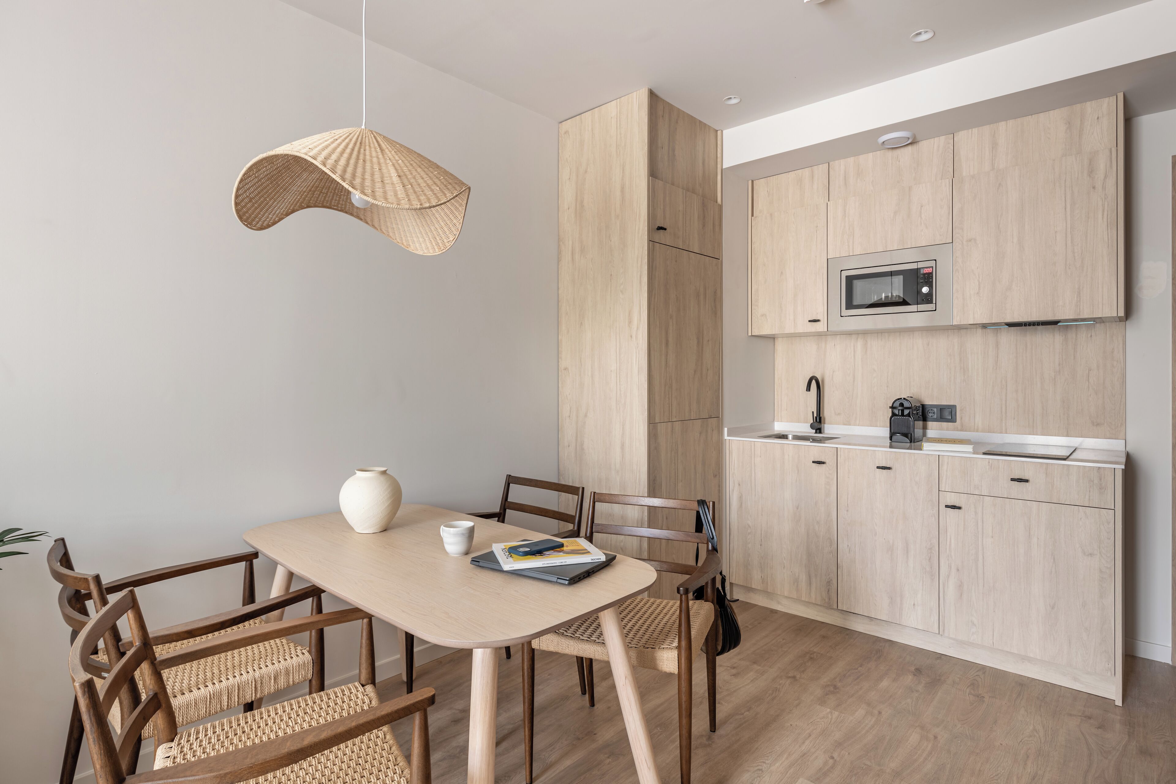 Una cocina moderna con armarios de madera, microondas y una lámpara colgante.
