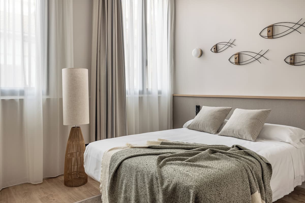 A bedroom with a bed, a floor lamp, and a wall with fish art.
