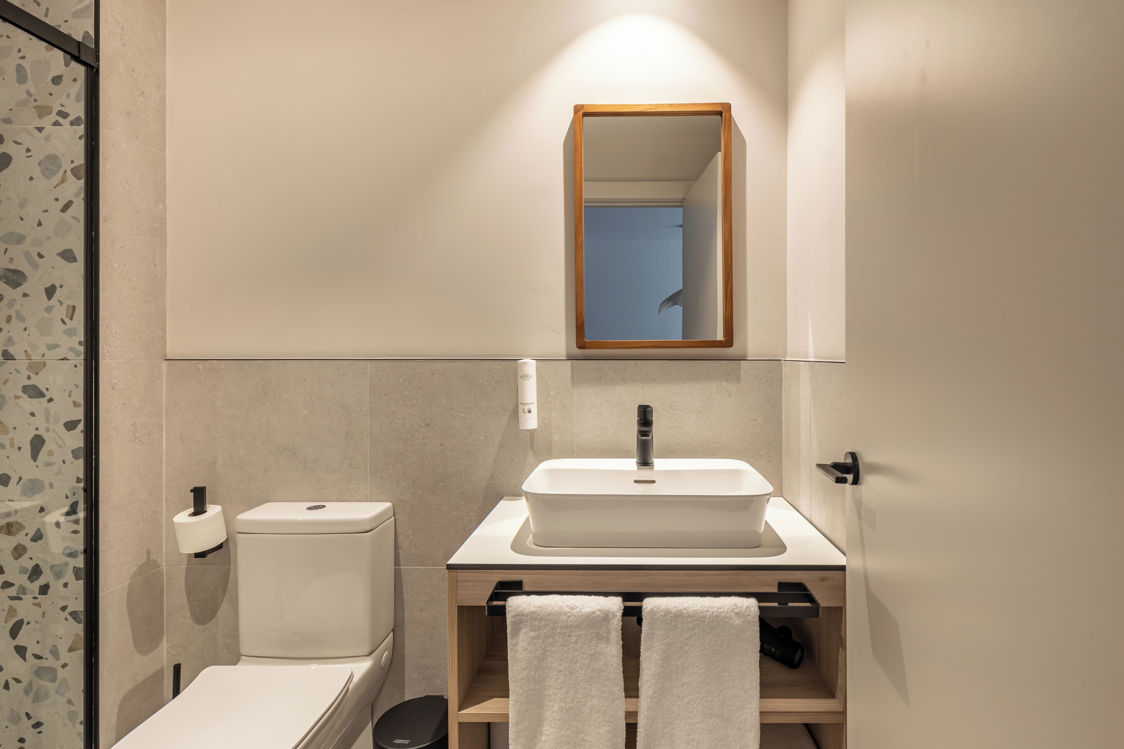 A modern bathroom with a toilet, sink, and mirror.
