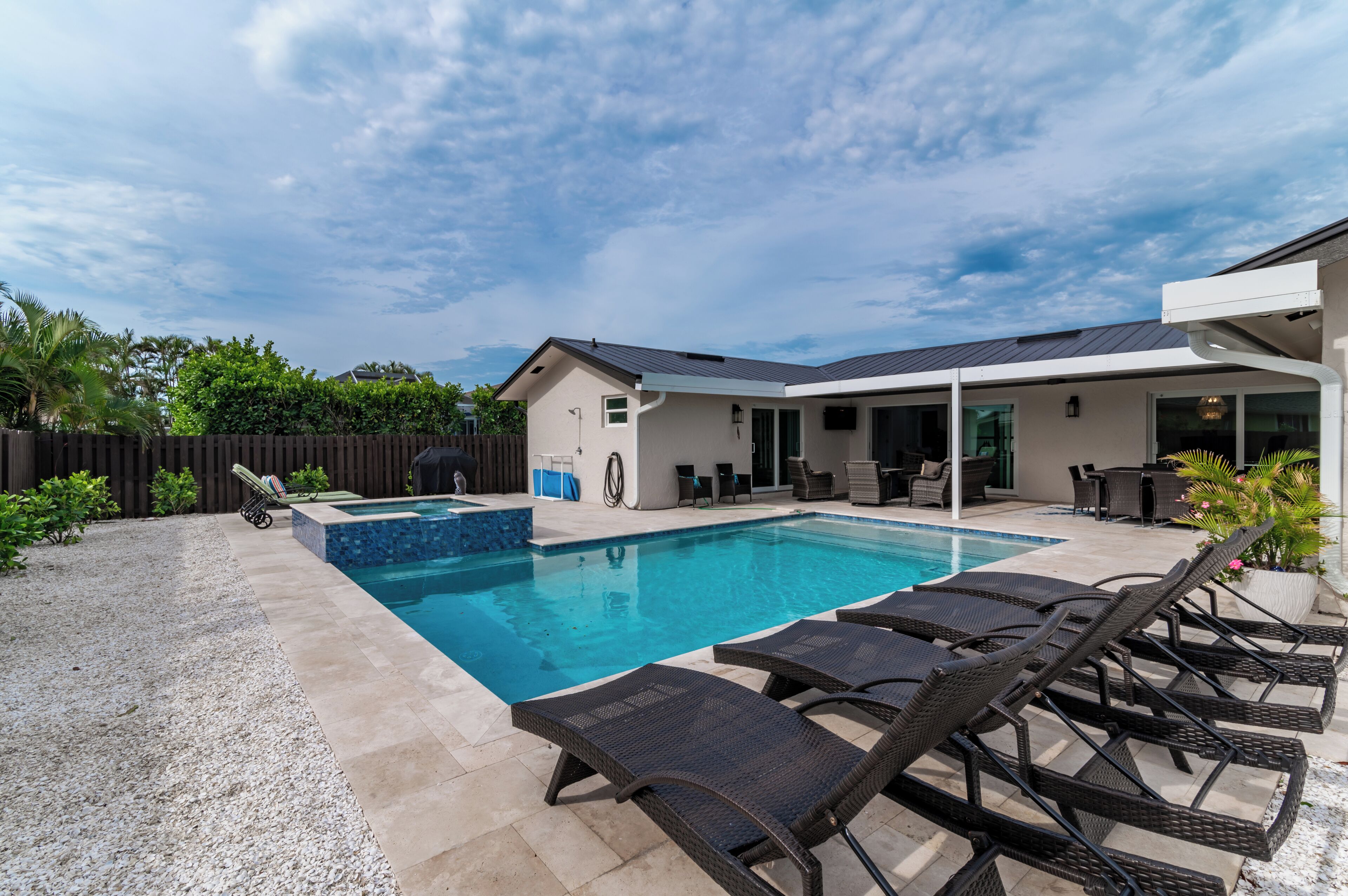 Un jardin avec une piscine, des chaises longues et un patio couvert.