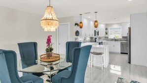 A modern kitchen with white cabinets, a marble backsplash, and stainless steel appliances. - Stunning 4 Bed I Heated Pool/Hot Tub (Marco Island)