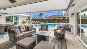 An outdoor patio area with a pool, wicker furniture, and a covered seating area. - Stunning 4 Bed I Heated Pool/Hot Tub (Marco Island)