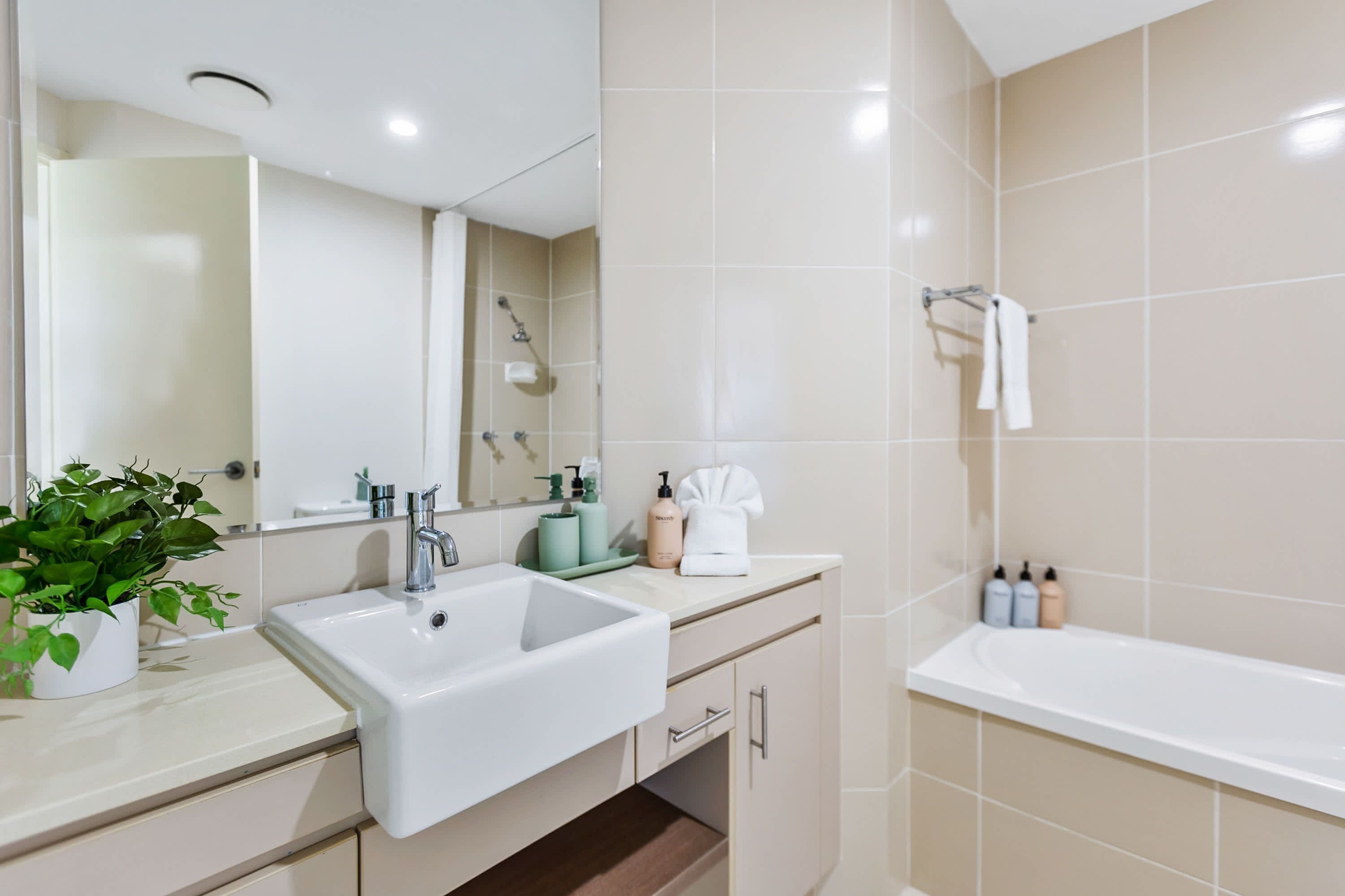 A modern bathroom with a white sink, a mirror, a shower, and a bathtub.