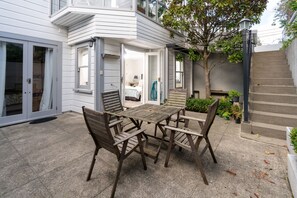 A patio with a wooden table and chairs, a small tree, and a staircase leading to a second floor. - A Historic Wellington Escape (Wellington)