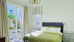 A bedroom with a bed, nightstands, a lamp, and a window with curtains. - A Historic Wellington Escape (Wellington)