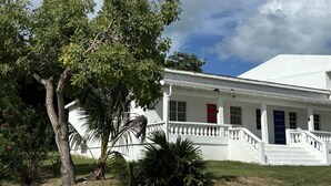 Un edificio blanco con puerta roja, columnas blancas y una escalera que conduce a la entrada.