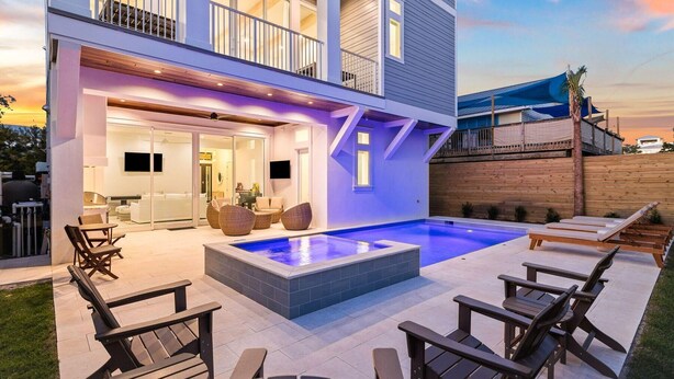 Une maison moderne dotée d’une piscine, d’un espace salon extérieur et d’un balcon.