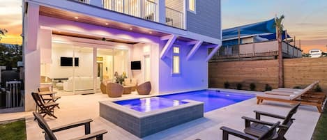 Une maison moderne dotée d’une piscine, d’un espace salon extérieur et d’un balcon.