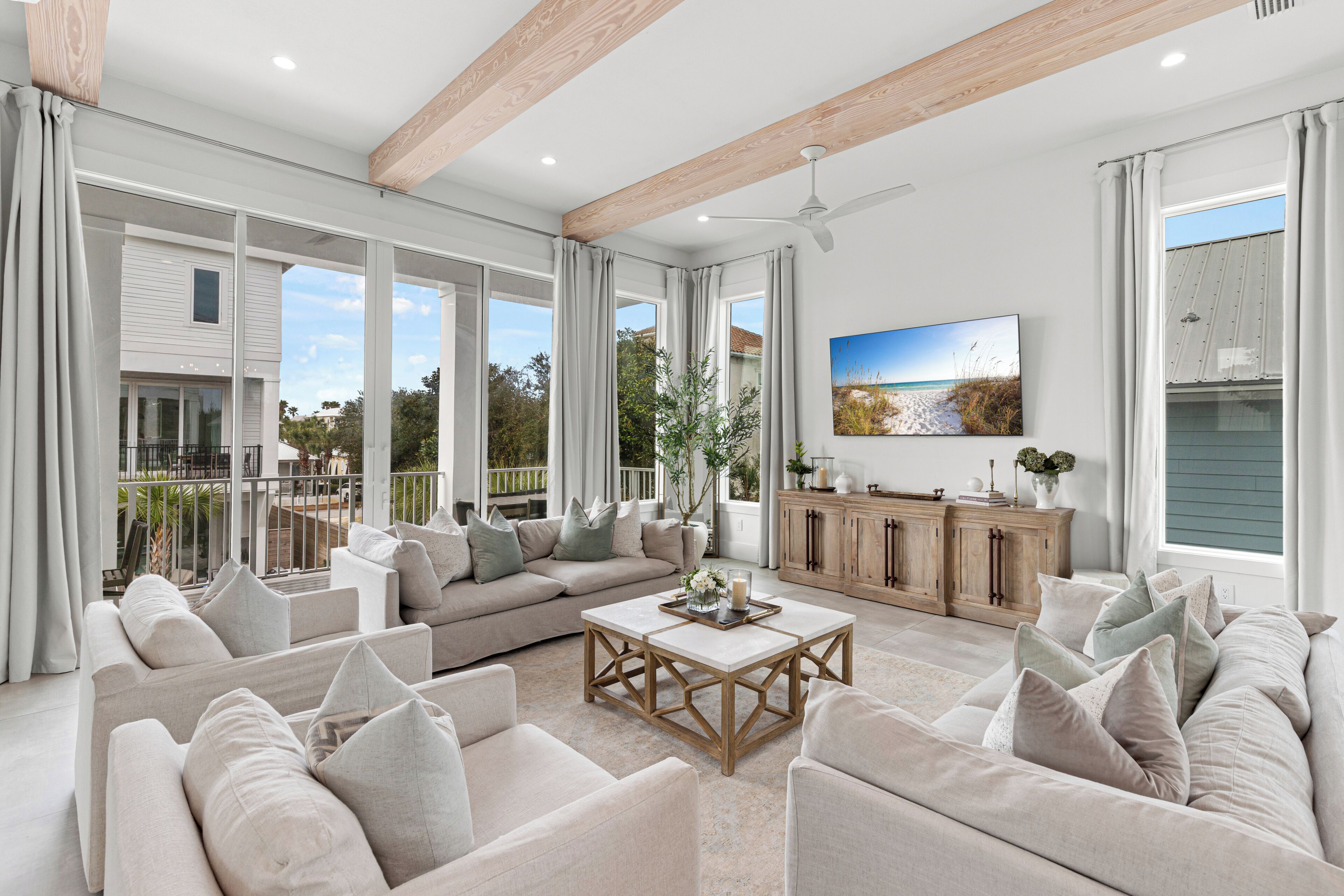 A spacious living room with a large sectional sofa, a coffee table, and a television mounted on the wall.