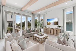 A spacious living room with a large sectional sofa, a coffee table, and a television mounted on the wall.
