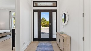 Un couloir avec un lit, une console et une porte donnant sur l’extérieur.