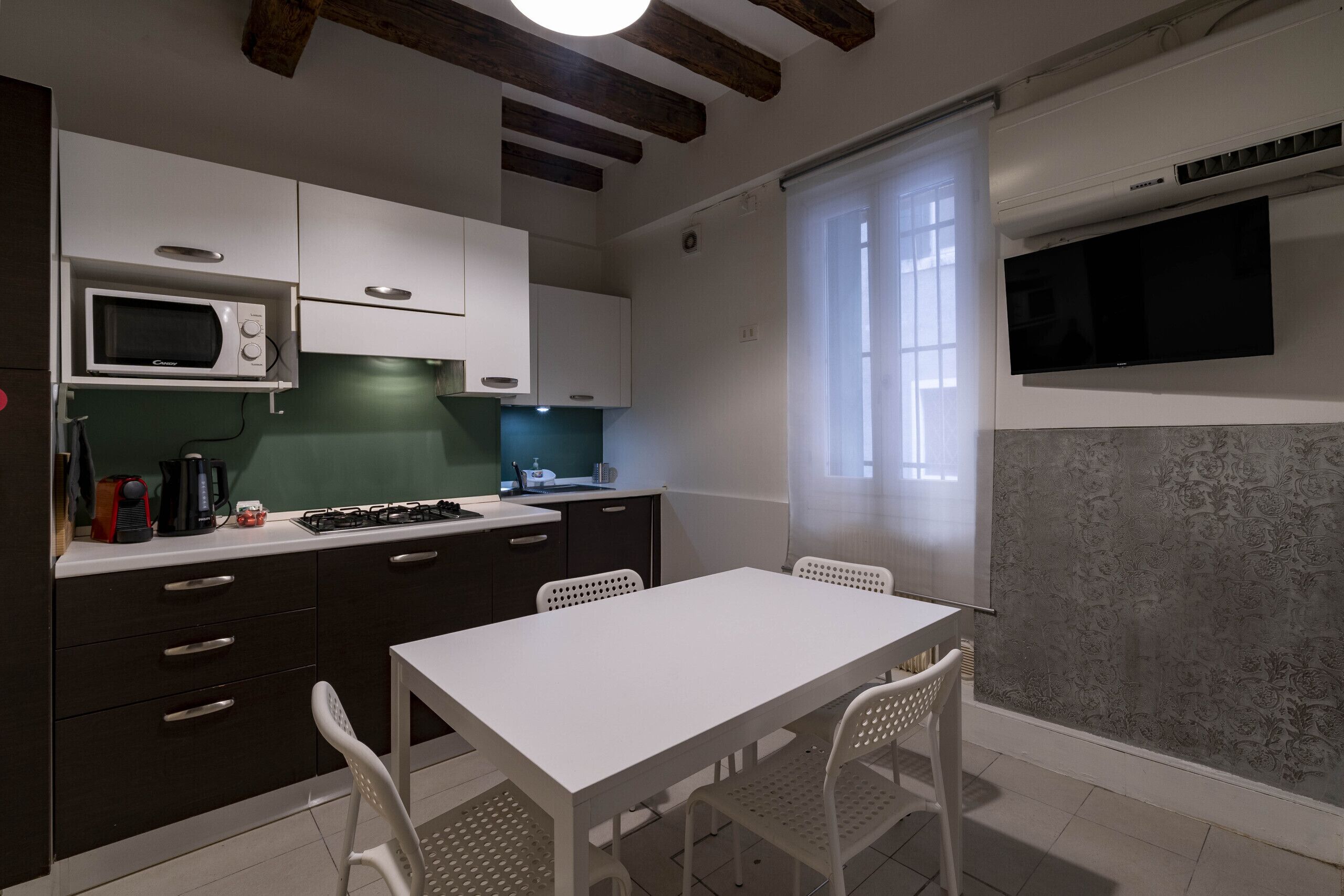 A compact kitchen with a white table and chairs, a microwave, and a gas stove.