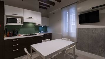 A compact kitchen with a white table and chairs, a microwave, and a gas stove.