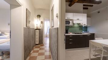 A compact kitchen with modern appliances, a dining area with a white table and chairs, and a checkered floor.