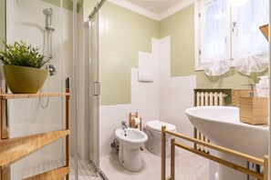 Een badkamer met douche, toilet, bidet en wastafel.
