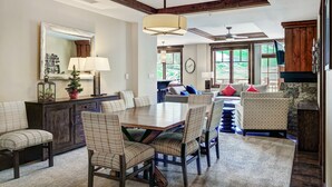 A spacious dining area with a wooden table and chairs, a large mirror, and a ceiling fan. - Luxury 4 Bedroom Condo on Peak 8 4 Condo (Breckenridge)
