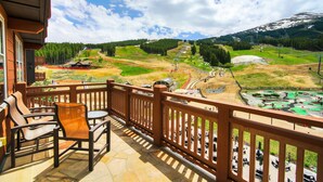 A balcony with wooden chairs and a view of a mountainous landscape with a ski slope. - Luxury 4 Bedroom Condo on Peak 8 4 Condo (Breckenridge)
