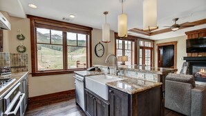 A modern kitchen with a large island, wooden cabinets, and a view of the outdoors. - Luxury 4 Bedroom Condo on Peak 8 4 Condo (Breckenridge)