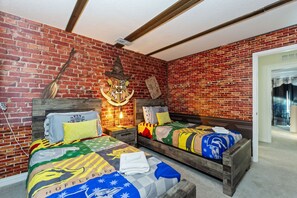 Quarto com duas camas de madeira, parede de tijolos e teto com vigas aparentes.