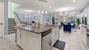 A spacious kitchen with a central island, modern appliances, and a dining area with a blue sofa. - Rear Views, Spa, Games Room, Pet Friendly, Resort Amenities 8 Bedroom Villa (Kissimmee)